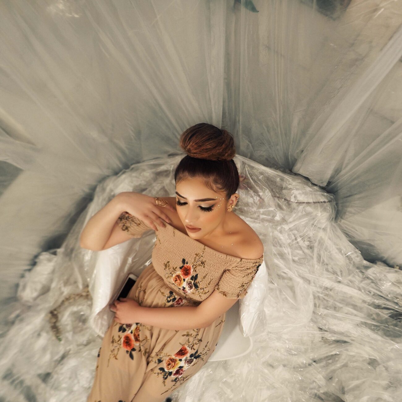 Bride sitting gracefully on bed in a white silk robe, preparing for her wedding day