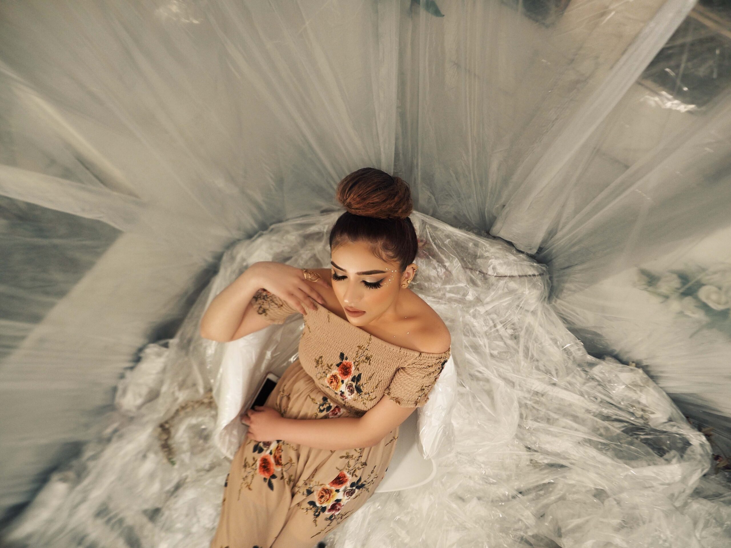 Bride sitting gracefully on bed in a white silk robe, preparing for her wedding day